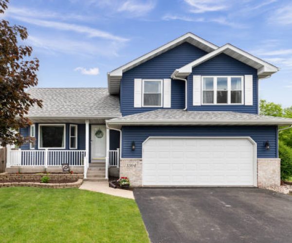 Exterior of a suburban home with blue siding, a white front porch, and white shutters.